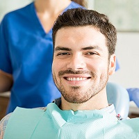 young male patient smiling with a female staff member behind him