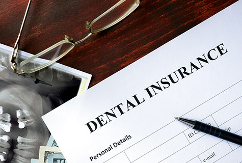 Dental insurance form on a desk with a pen and glasses